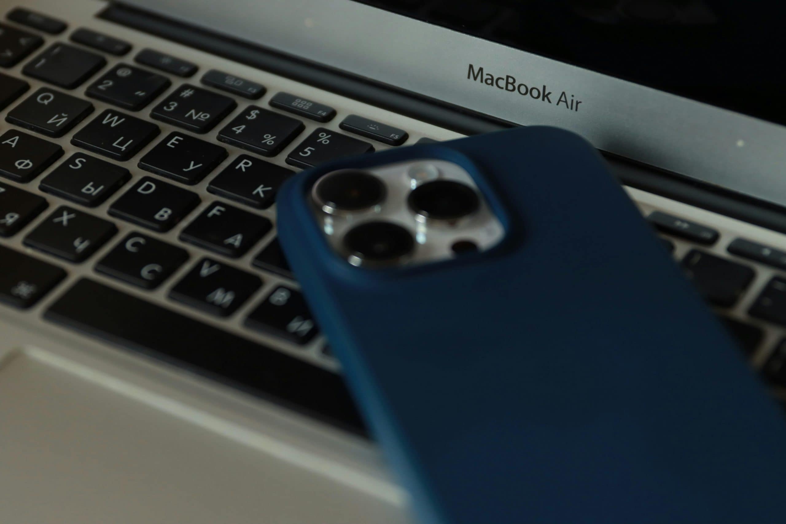 An iPhone aesthetically placed on the keyboard of a MacBook Pro.