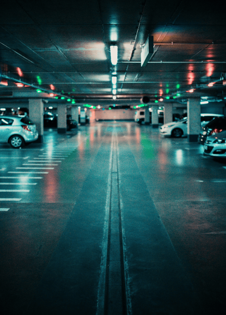 a parking lot at night with few cars parked.