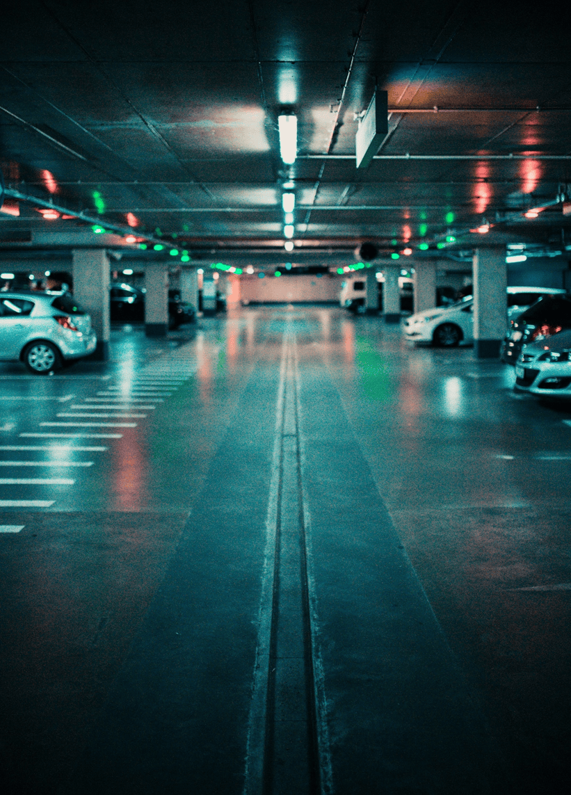 a parking lot at night with few cars parked.