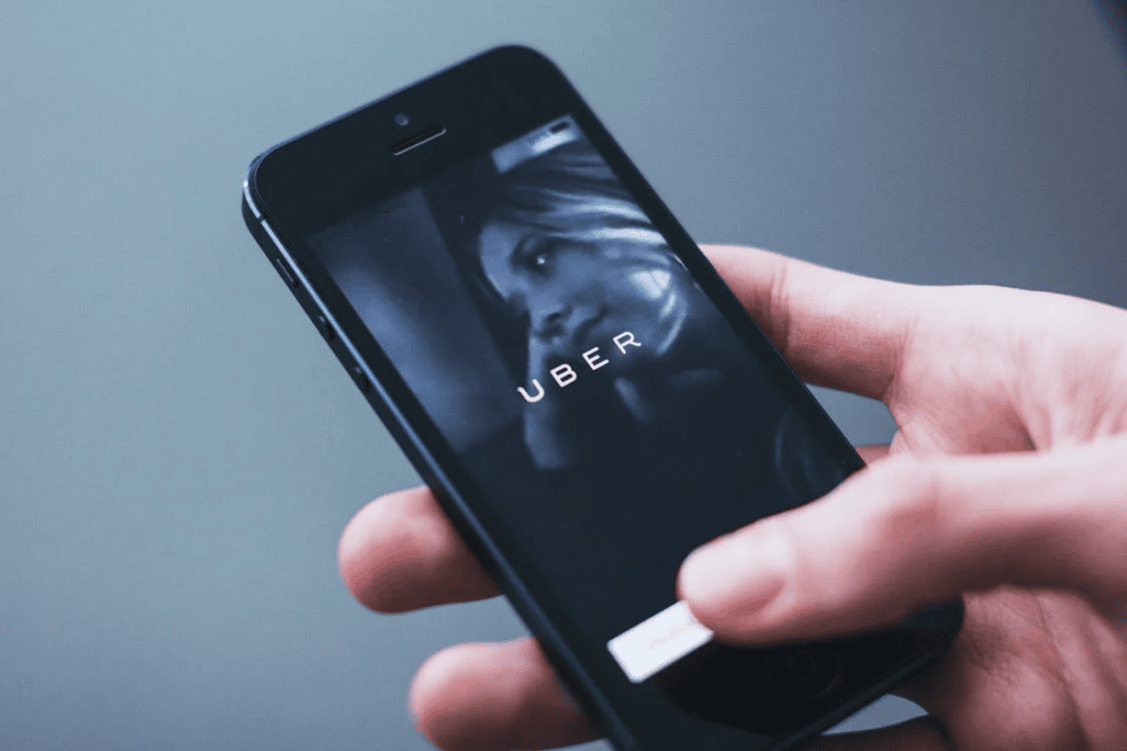 Hand holding a smartphone displaying the Uber app loading screen.